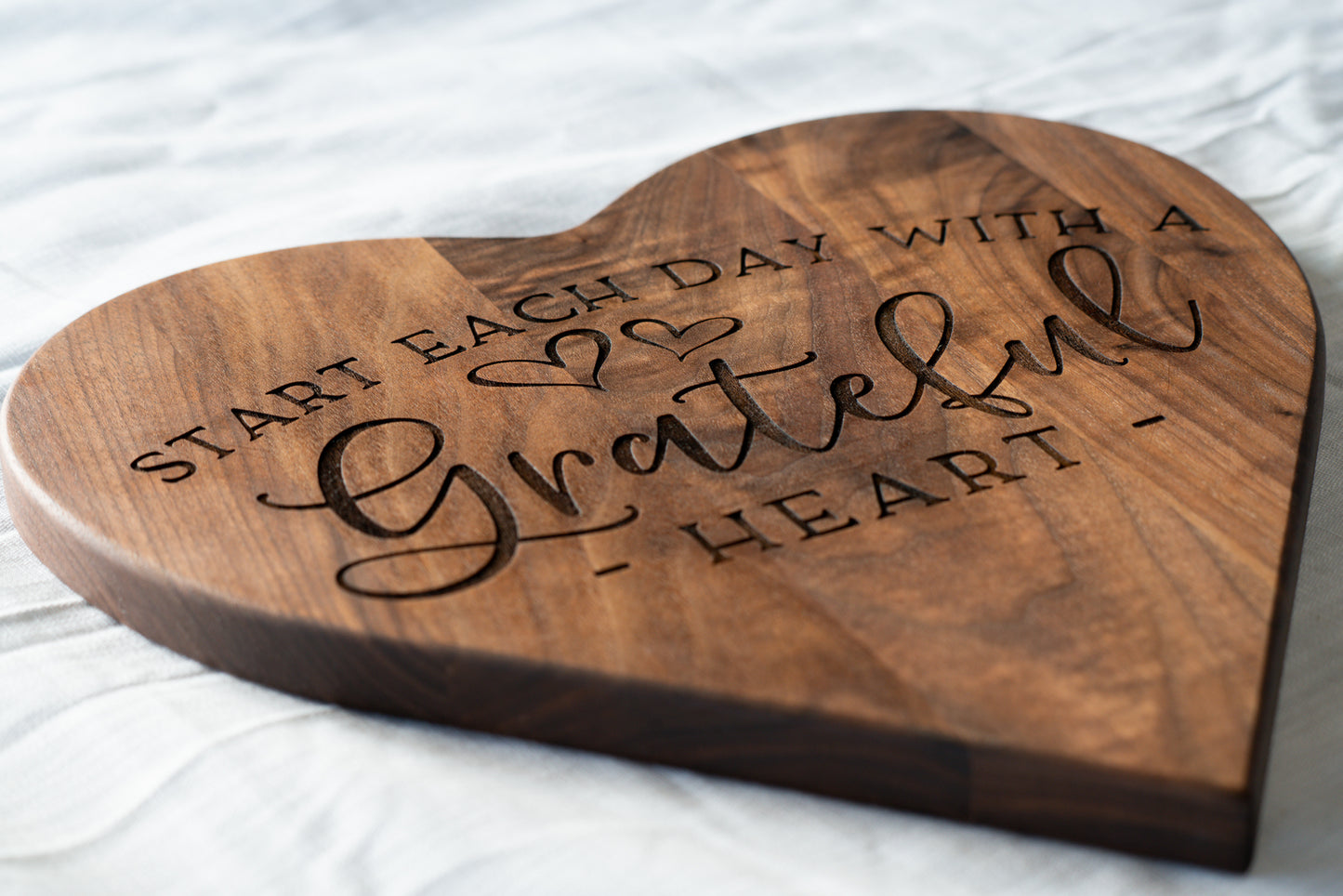 Side view of "Start each day with a grateful heart" cutting board. Heart shaped walnut cutting board.